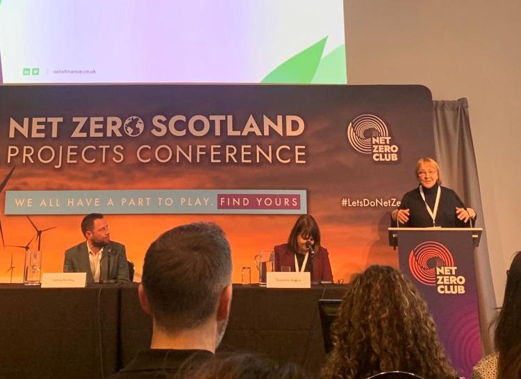 Speakers of the Net Zero Scotland Conference, two people sat on panel with a speaker on the podium.